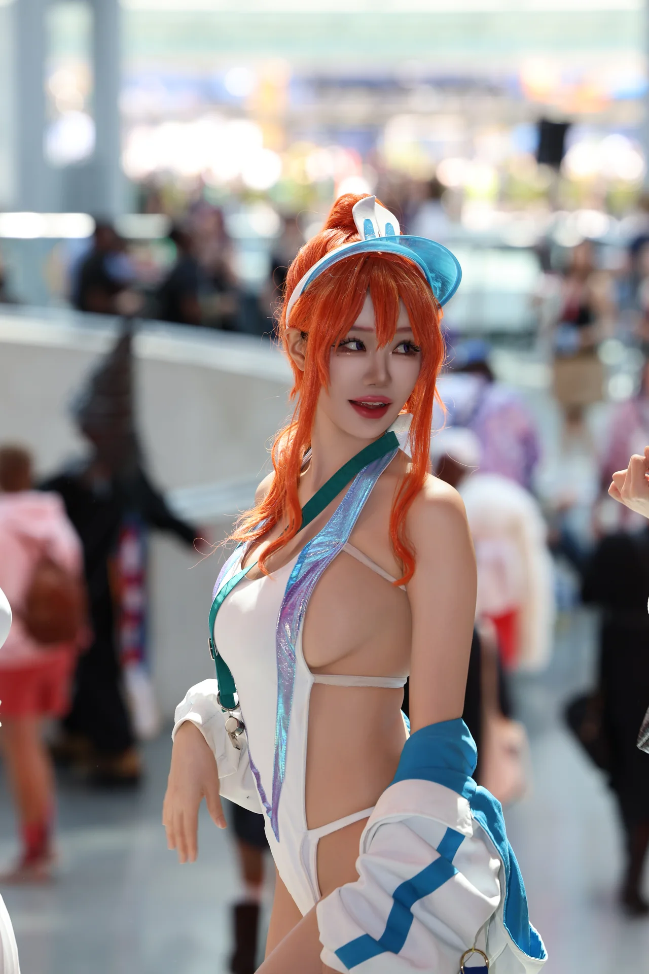 An orange-haired cosplayer turning toward the camera in a sunlit hall