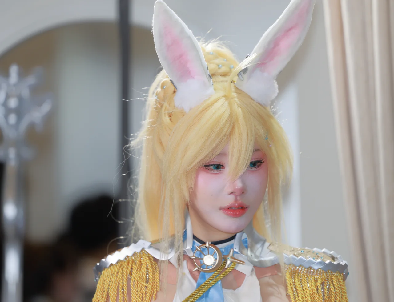 Close-up of a blonde cosplayer wearing tall rabbit ears and gold epaulettes