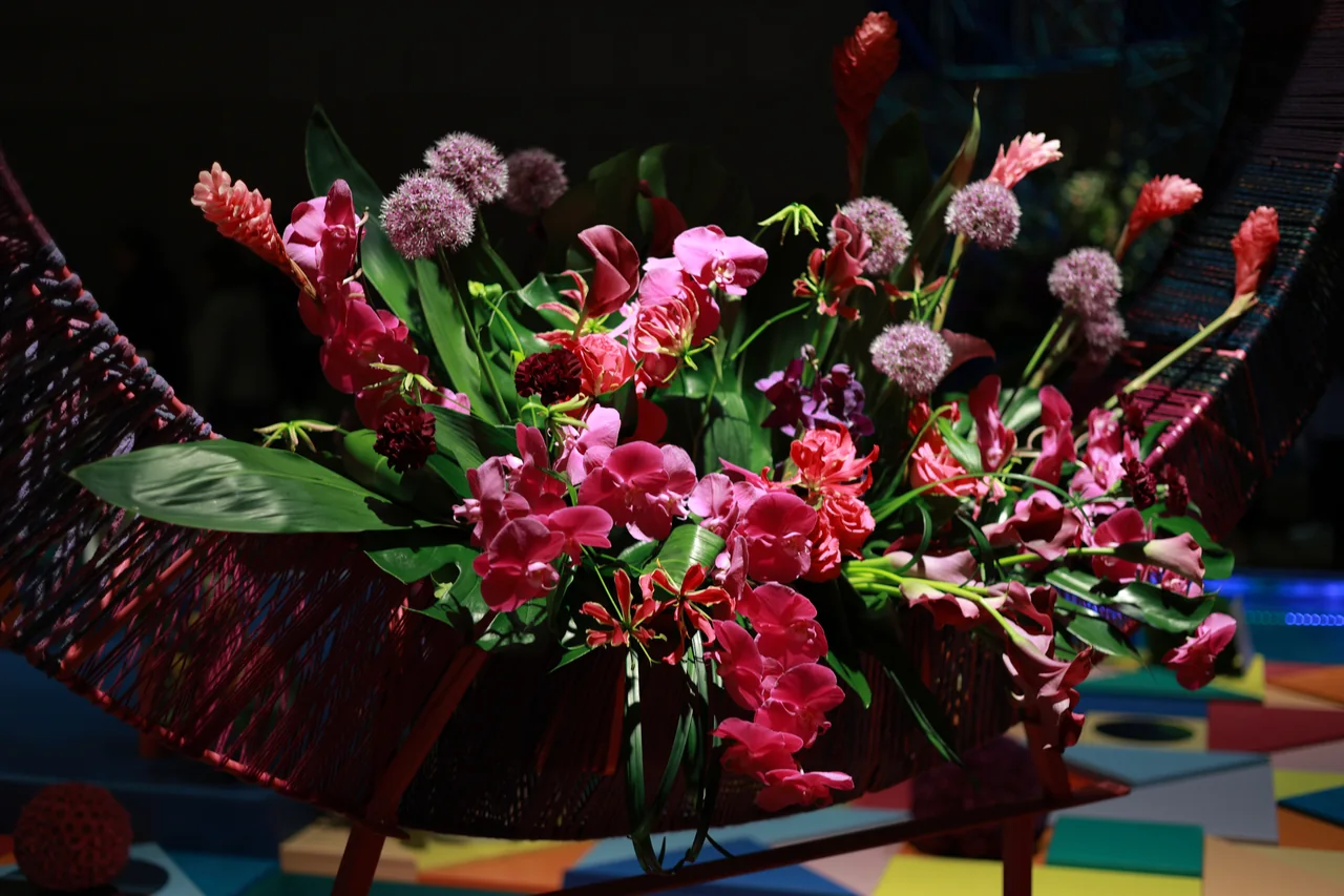 Pink and red flowers with round purple blooms arranged in a dark woven display