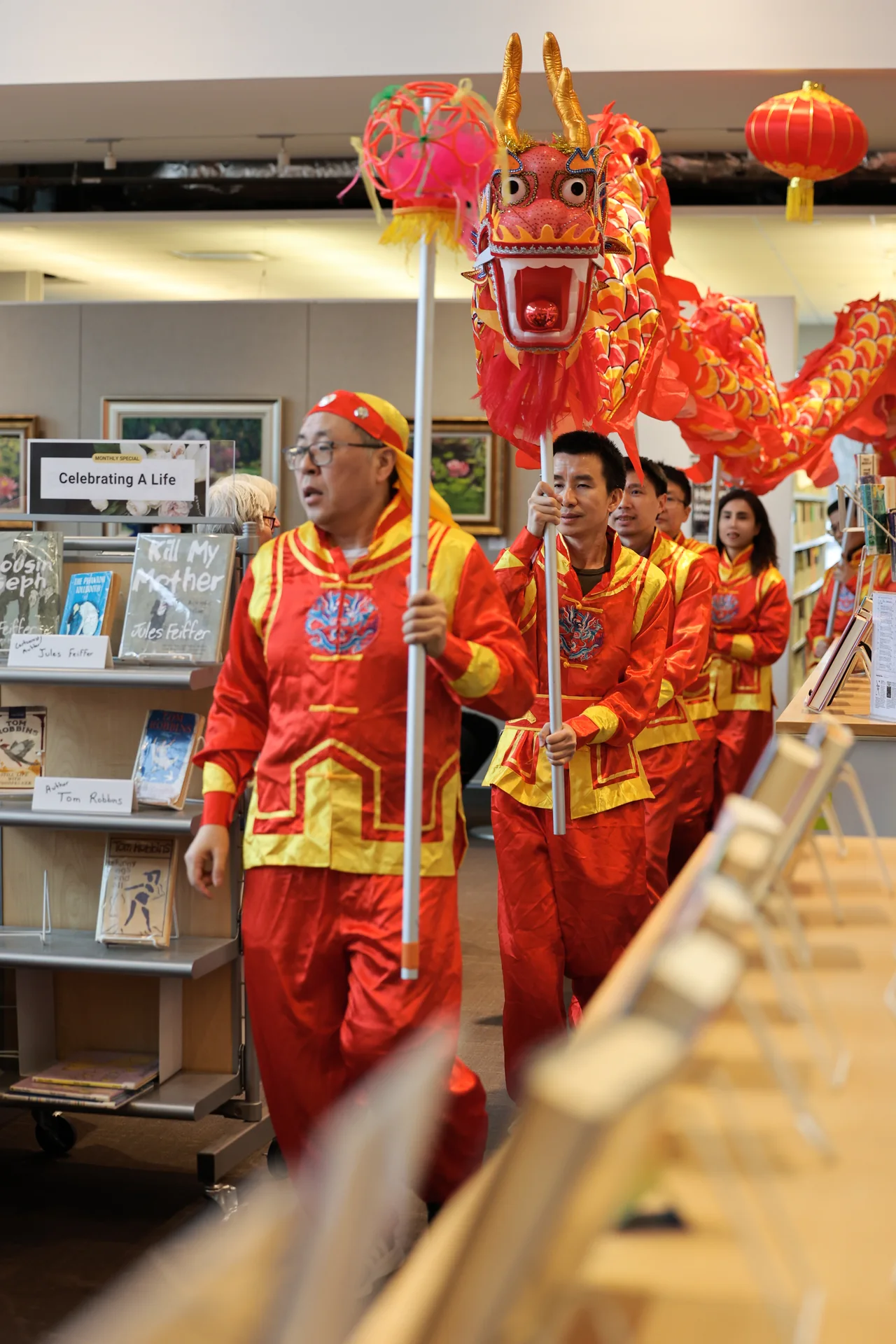 Dragon dance performers entering a library between shelves