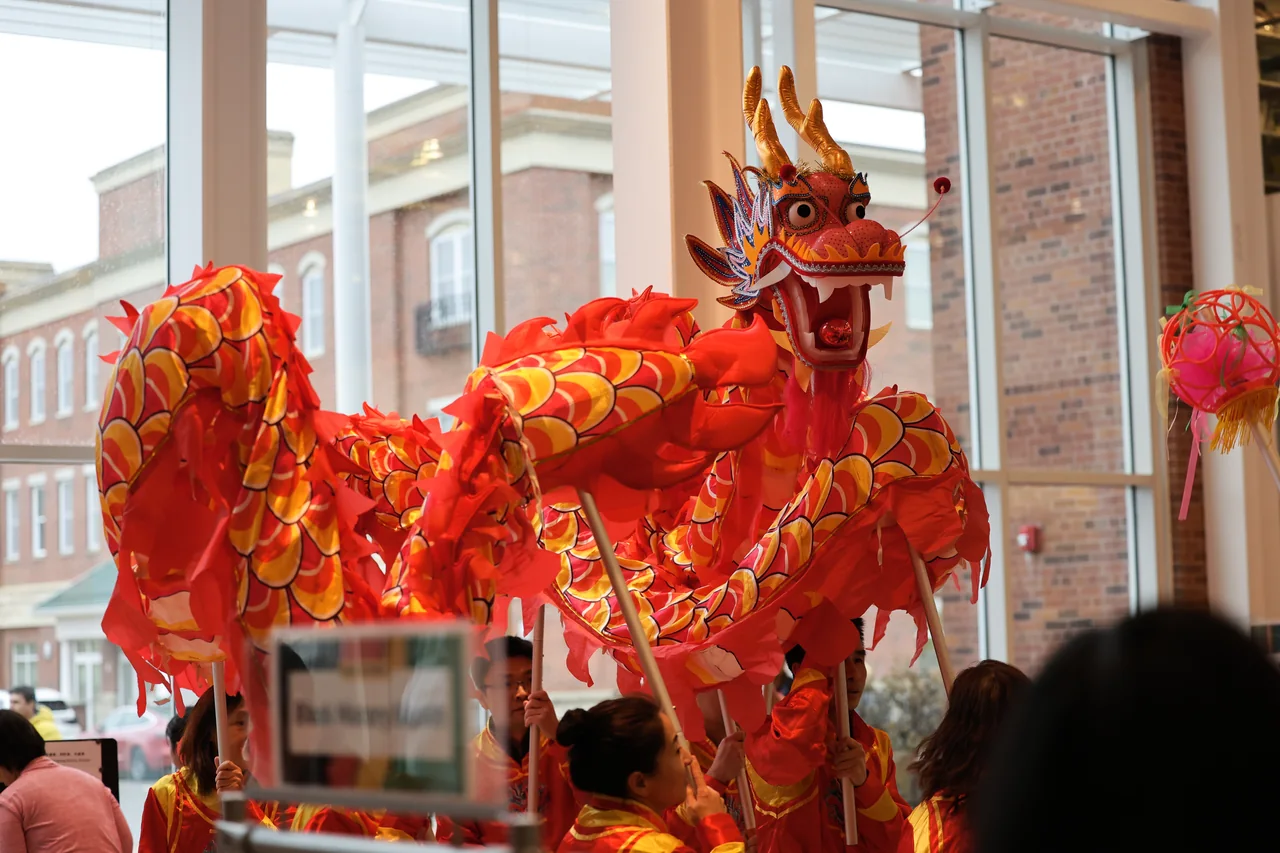 A dragon dance puppet lifted high beside a library window