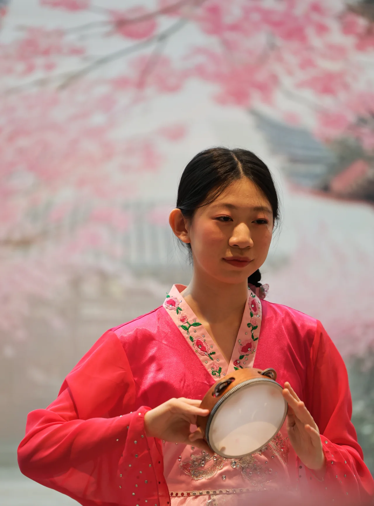 A performer in pink holding a small hand drum