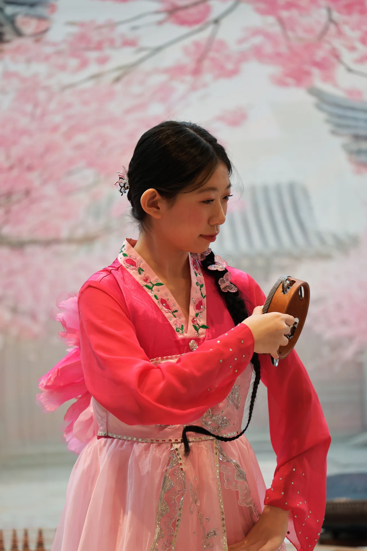 A performer in pink looking down at a small percussion instrument