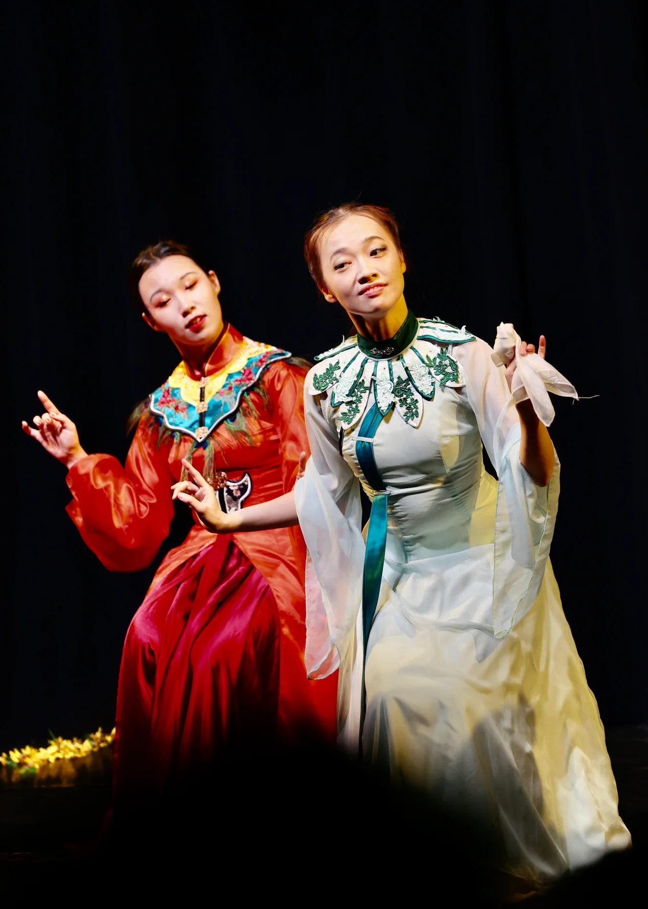 Two performers in embroidered costumes gesturing on stage